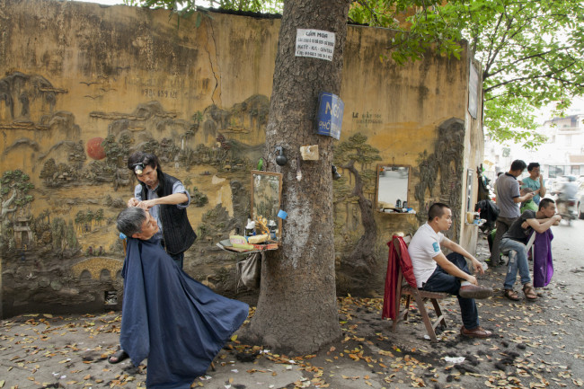 As Vietnam enters the modern era, Catherine strives to capture the country’s timeless scenes: Barbers on the street await customers in Hanoi.