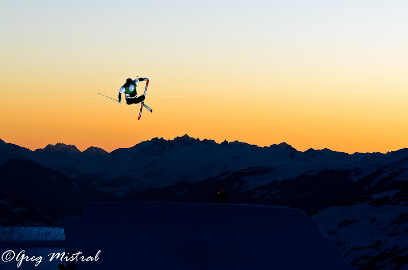 Skier jumping at sunset with mountains in the background