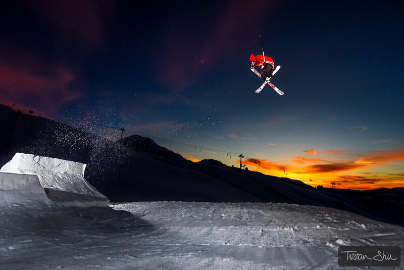 Skier doing a tail grab at sunset